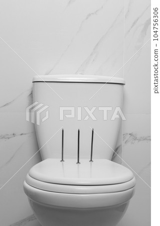 Toilet bowl with nails near marble wall. Hemorrhoids concept Toilet bowl with nails near marble wall. Hemorrhoids concept 104756306