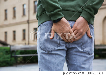Man suffering from hemorrhoid pain outdoors, back view 104756311