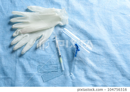 Anoscope, rubber gloves and syringe on light blue fabric, flat lay. Hemorrhoid treatment 104756316