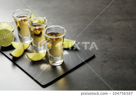 Mexican Tequila shots with salt and lime slices on grey table. Space for text Mexican Tequila shots with salt and lime slices on grey table. Space for text 104756387