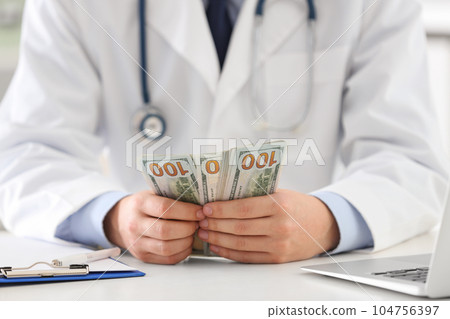 Doctor with bribe at desk in clinic, closeup. Corrupted medicine 104756397