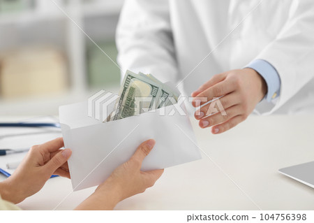 Patient giving bribe to doctor in clinic, closeup. Corrupted medicine 104756398