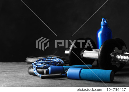 Gym equipment and accessories on stone floor against dark background Gym equipment and accessories on stone floor against dark background 104756417