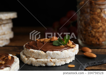 Puffed rice cakes with chocolate spread, nuts and mint on slate board, closeup Puffed rice cakes with chocolate spread, nuts and mint on slate board, closeup 104756528