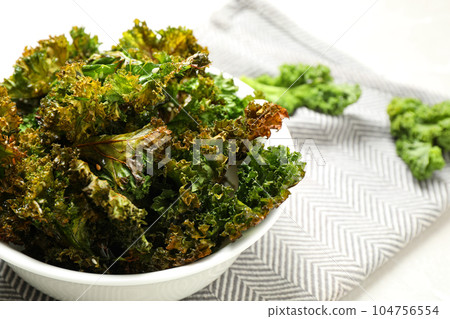 Tasty baked kale chips in bowl, closeup 104756554