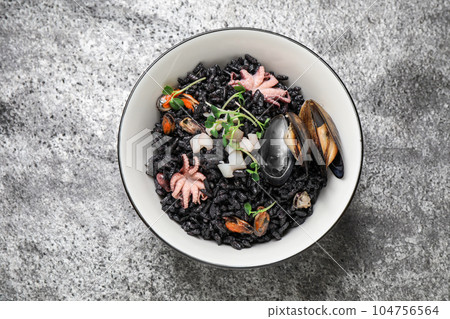 Delicious black risotto with seafood in bowl on light grey table, top view Delicious black risotto with seafood in bowl on light grey table, top view 104756564