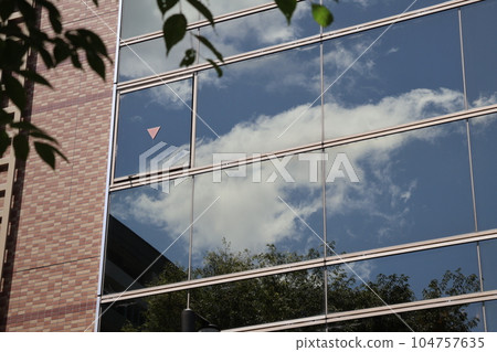 Landscape with blue sky, white clouds and green leaves in the window of the building 104757635