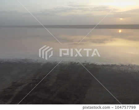 foggy sunset on the horizon, with the sun's rays casting a warm, golden glow foggy sunset on the horizon, with the sun's rays casting a warm, golden glow 104757799