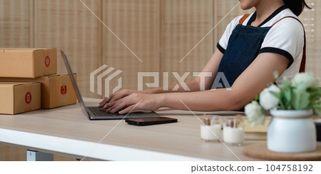 Young Asian business woman working at warehouse preparing SME package box for delivery at small business home 104758192