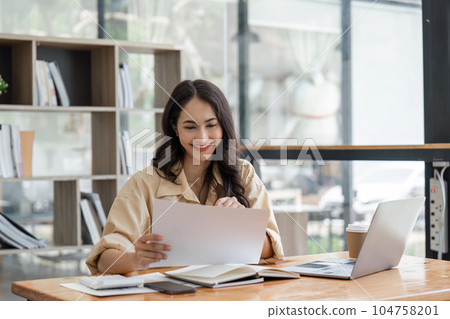 Successful smiling mature businesswoman using laptop and computer while doing some paperwork at the office Successful smiling mature businesswoman using laptop and computer while doing some paperwork at the office 104758201