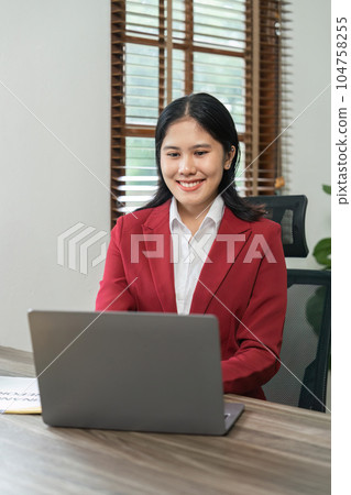 Portrait of beautiful smiling young businesswoman sitting at bright in office modern work and typing on laptop 104758255
