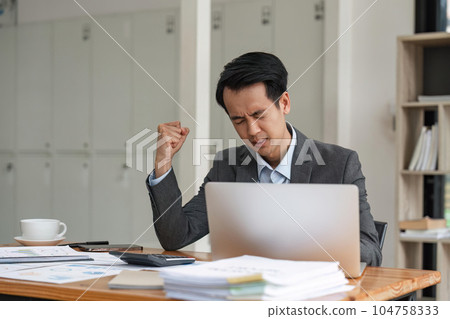 business man stress paperwork and deadline concept stressed businessman with papers and charts sitting at table in office business man stress paperwork and deadline concept stressed businessman with papers and charts sitting at table in office 104758333