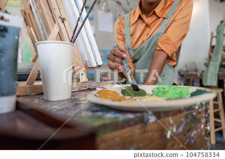 Hands of female artist artist with palette painting at art studio Hands of female artist artist with palette painting at art studio 104758334
