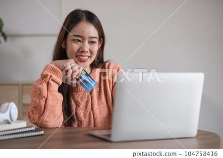 Image of young asian woman order online, shopping from home. Girl enter credit card info on webside to make purchase, using laptop to shop, paying bills with computer 104758416