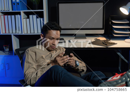 Overworked young Asian office employee working on laptop computer overtime in office at night Overworked young Asian office employee working on laptop computer overtime in office at night 104758665