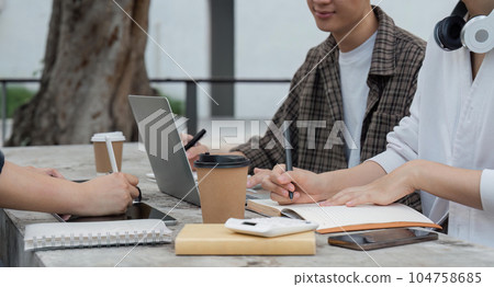 Group of happy students checking results on laptop and tablet while sitting on college campus, concept of education, technology and project work discussion Group of happy students checking results on laptop and tablet while sitting on college campus, concept of education, technology and project work discussion 104758685