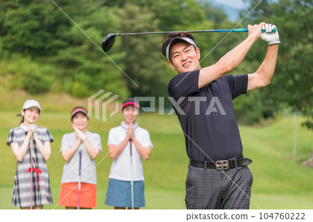 男子在高爾夫球場打高爾夫球,女高爾夫球手觀看揮桿 男子在高爾夫球場打高爾夫球,女高爾夫球手觀看揮桿 104760222