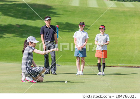 高爾夫球手男女在高爾夫球場的果嶺上打高爾夫球（推桿） 104760325