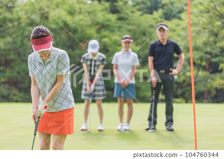 Golfer woman (putter) playing golf on the green of the golf course Golfer woman (putter) playing golf on the green of the golf course 104760344
