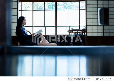 A high school girl reading a book leisurely in a Japanese-style room 104762886