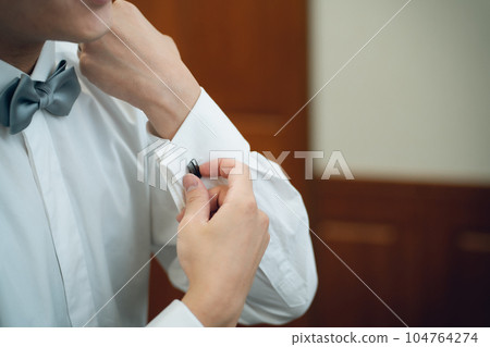 Groom/bridegroom (cufflinks) preparing for wedding/ceremony/reception in waiting room/brides room 104764274