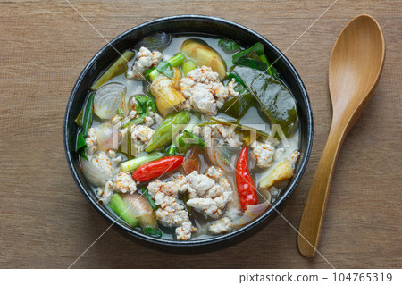 close up of spicy minced pork clear soup in a ceramic bowl on wooden table. asian homemade style healthy food concept 104765319