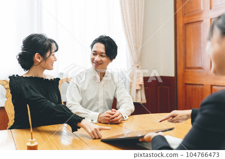 Young Asian couple consulting and meeting at a wedding hall / bridal fair Young Asian couple consulting and meeting at a wedding hall / bridal fair 104766473