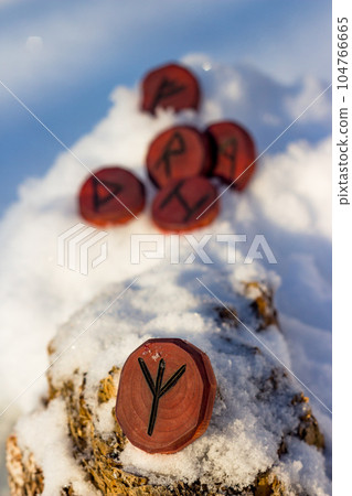 Rune inverted Algiz (Elhaz) carved from wood in the snow Rune inverted Algiz (Elhaz) carved from wood in the snow 104766665