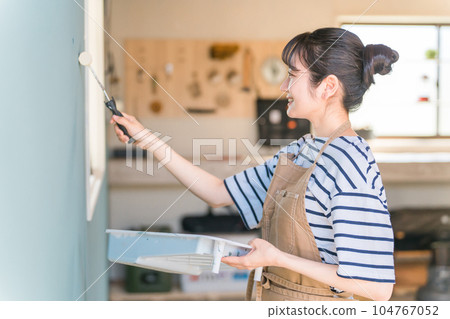 Japanese woman painting the wall (paint roller) Japanese woman painting the wall (paint roller) 104767052