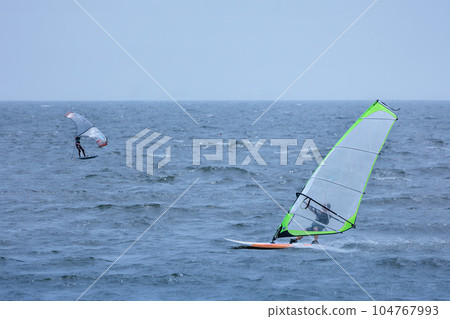 Windsurfing around the water in the refreshing breeze Windsurfing around the water in the refreshing breeze 104767993