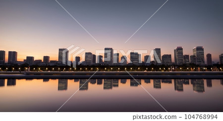 colorful sunset skyline city panorama with downtown bank buildings bridge and city centre. Evening sky with clouds after rain and reflection in rivers water at blue hour. Generative AI colorful sunset skyline city panorama with downtown bank buildings bridge and city centre. Evening sky with clouds after rain and reflection in rivers water at blue hour. Generative AI 104768994