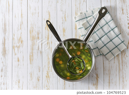 homemade green bean soup with vegetables on a wooden table, top view. homemade green bean soup with vegetables on a wooden table, top view. 104769523