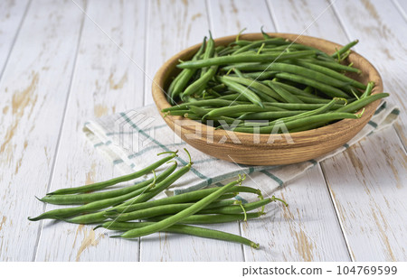 fresh green beans in a wooden bowl on a kitchen table, copy space for text. 104769599