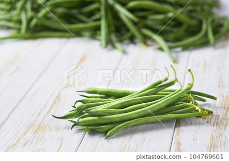 bundle of green beans on a white wooden table, selective focus. 104769601