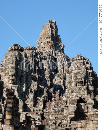 Capture of the Bayon Temple's stone towers in Cambodia under a clear blue sky, an example of medieval Khmer architecture. 104771632