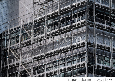 Building exterior wall construction: sunlight and temporary scaffolding 104771866
