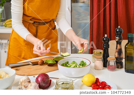 Unrecognisable woman adds slices of avocado in probiotic salad Unrecognisable woman adds slices of avocado in probiotic salad 104772349
