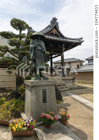 A temple bell and a statue of Shinran Shonin at Komyoji Temple in Suita City, Osaka Prefecture (taken on April 29, 2023) 104774655