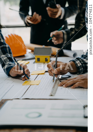 Working as a team architect and designer working on blueprint project of new apartments. Photo concept of work on technical drawings in office. 104774811