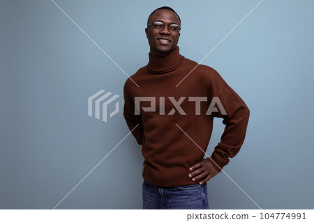 elegant young american brunet man in stylish brown sweater posing over isolated blue background with elegant young american brunet man in stylish brown sweater posing over isolated blue background with 104774991