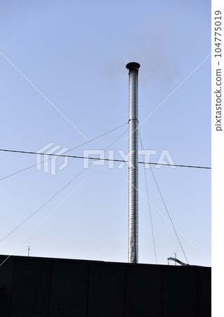 Metal silver pipe with smoke on the background of the sky. A long chimney. Metal silver pipe with smoke on the background of the sky. A long chimney. 104775019