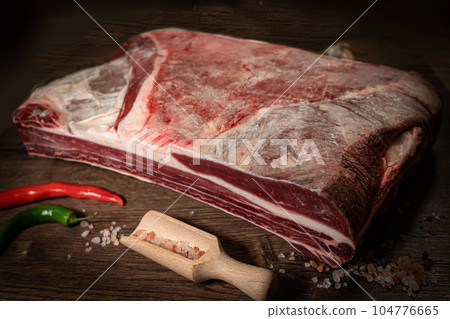 Organic machete or hanger butcher steak, near butcher knife with pink pepper and rosemary. Black background. Top view. side view 104776665
