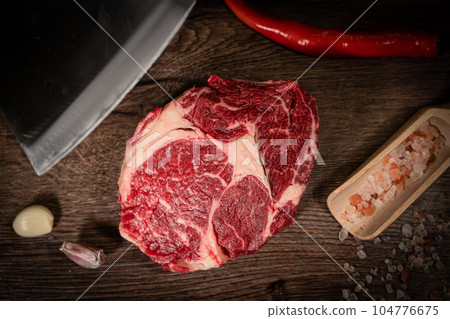 Organic machete or hanger butcher steak, near butcher knife with pink pepper and rosemary. Black background. Top view. side view 104776675