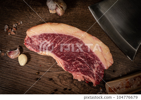Organic machete or hanger butcher steak, near butcher knife with pink pepper and rosemary. Black background. Top view. side view 104776679