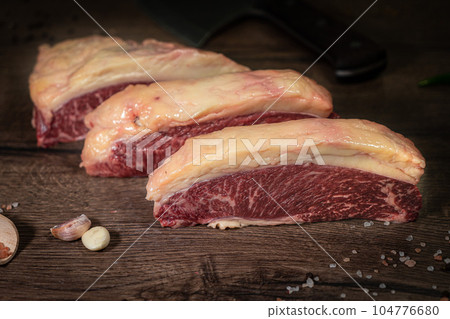 Organic machete or hanger butcher steak, near butcher knife with pink pepper and rosemary. Black background. Top view. side view 104776680