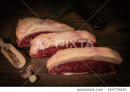 Organic machete or hanger butcher steak, near butcher knife with pink pepper and rosemary. Black background. Top view. side view Organic machete or hanger butcher steak, near butcher knife with pink pepper and rosemary. Black background. Top view. side view 104776681