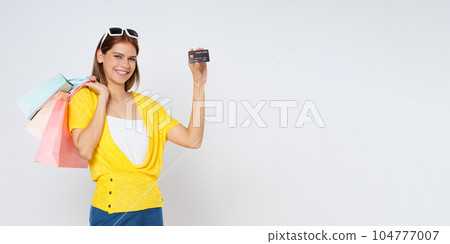 Happy young woman holding shopping bags and showing credit card isolated on white background. Happy young woman holding shopping bags and showing credit card isolated on white background. 104777007