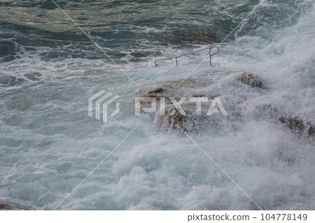 Sea waves crashing against the rocks of mediterranean shore Sea waves crashing against the rocks of mediterranean shore 104778149