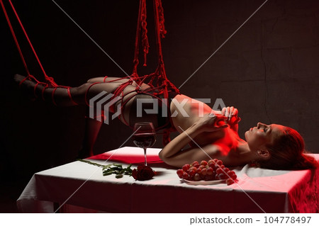 Sexy topless female tied with ropes during BDSM party Sexy topless female tied with ropes during BDSM party 104778497