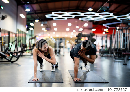 Athletic Sportsman and Sportswoman Doing Push Ups Together at Fitness Gym 104778737